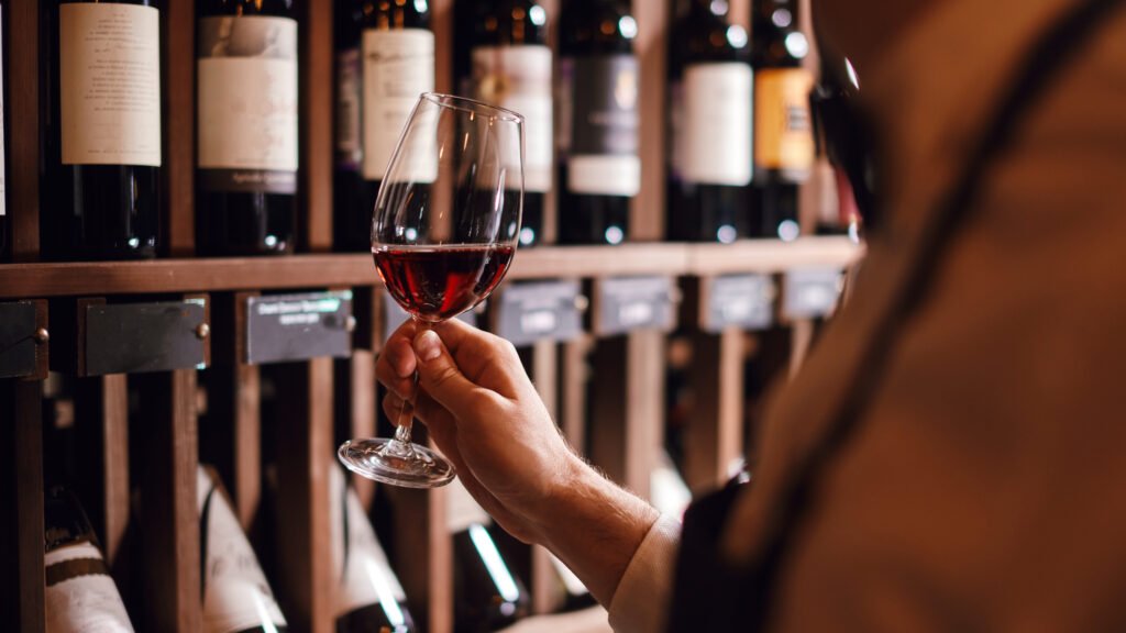 wine expert holds a glass of wine, looks at tint and smells flavor, degustating